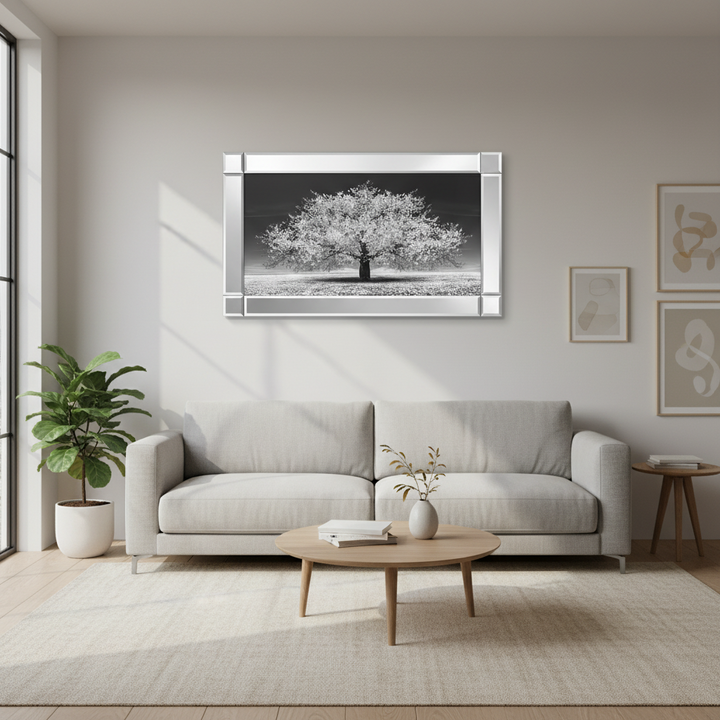 Modern living room with a gray sofa, round wooden coffee table, and framed black and white tree artwork on the wall.